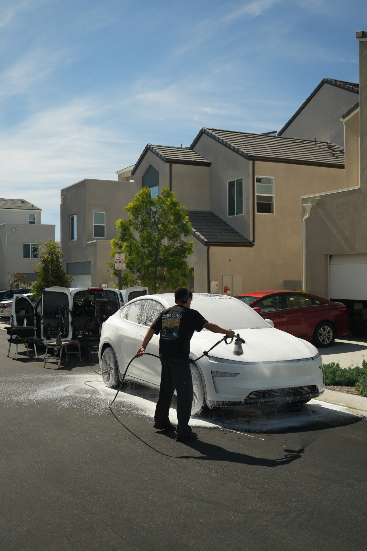 Irvine Details detailer washing a white car at a customer's driveway
